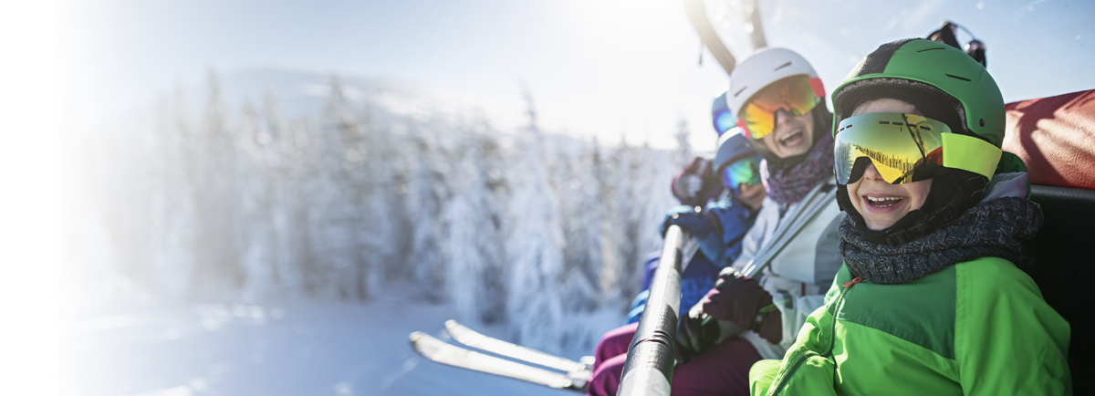 Rodzina uśmiecha się podczas jazdy wyciągiem krzesełkowym w słoneczny, zimowy dzień na stokach narciarskich