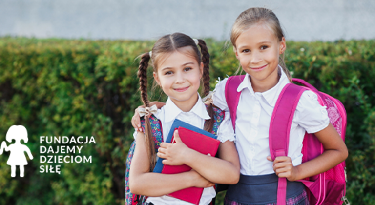 Dwoje dzieci w szkolnych mundurkach stojących z plecakami na tle zielonego żywopłotu, obok logo Fundacji Dajemy Dzieciom Siłę