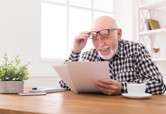 Starszy Pan przegląda wyliczenia swojej emerytury którą otrzymuje w Polsce