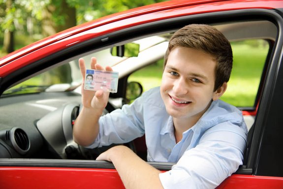 młody kierowca pokazuje swoje prawo jazdy