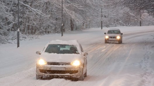 auta jadą po zaśnieżonej drodze