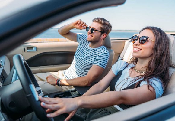 kobieta kierująca samochodem, obok mężczyzna siedzący na miejscu pasażera z przodu