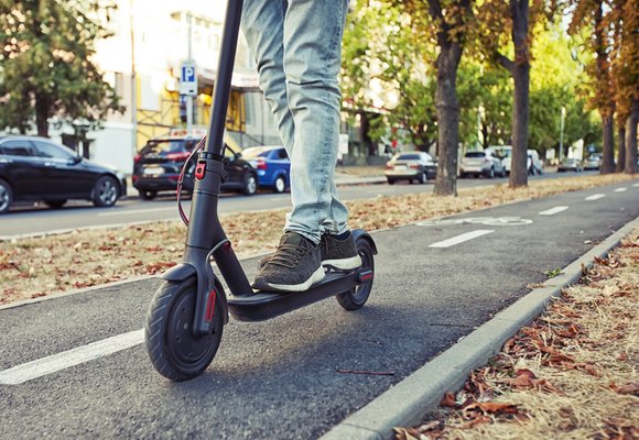 Osoba jadąca hulajnogą elektryczną po ścieżce rowerowej, ponieważ w tym miejscu nie można jeździć po ulicy
