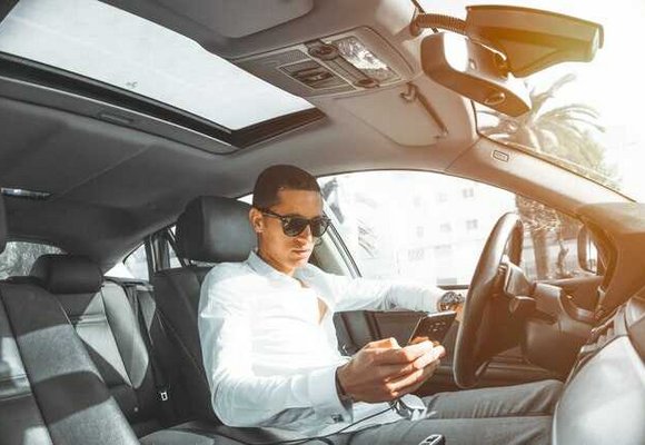 Mężczyzna w samochodzie sprawdza na telefonie wpływ cesji leasingu na ubezpieczenie