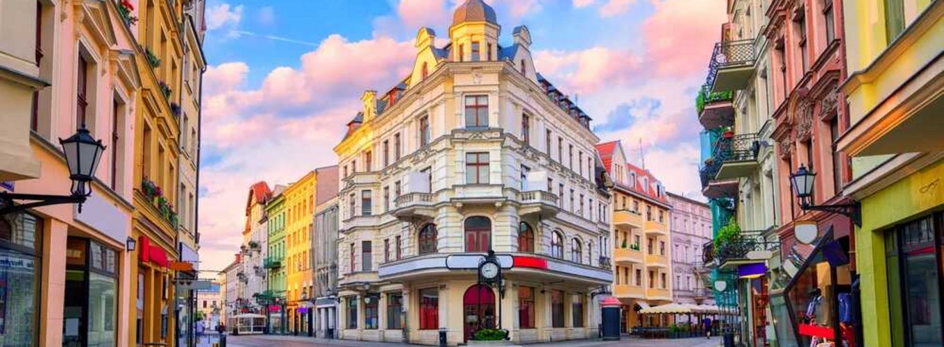 Malownicza, kolorowa ulica w Toruniu o zachodzie słońca z zabytkowymi kamienicami i latarniami. Idealne miejsce na spacer z karta EKUZ zapewniającą dostęp do opieki zdrowotnej podczas podróży po Europie.