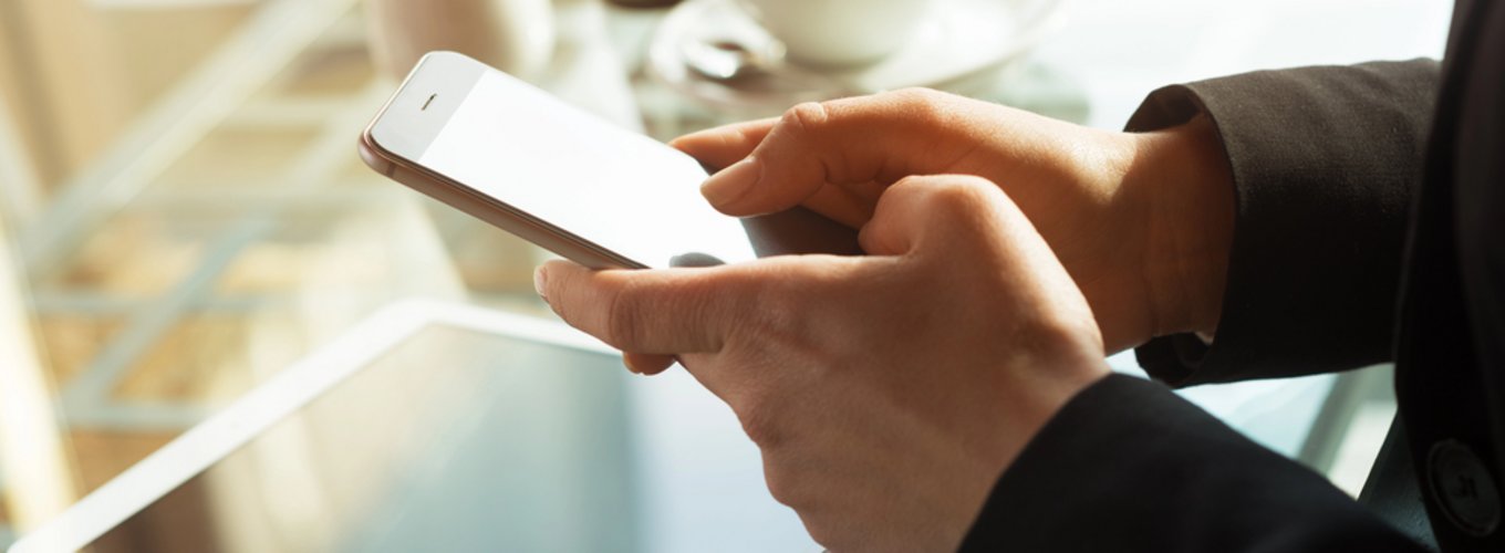 Osoba korzystająca ze smartfona przy stole, dla którego kupuje ubezpieczenie ekranu telefonu online