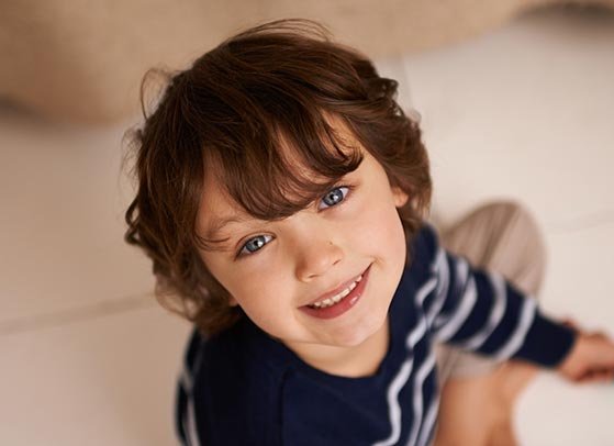 Radosne dziecko patrzy w obiektyw aparatu.