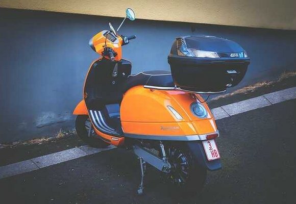 zaparkowany pomarańczowy skuter z bagażnikiem