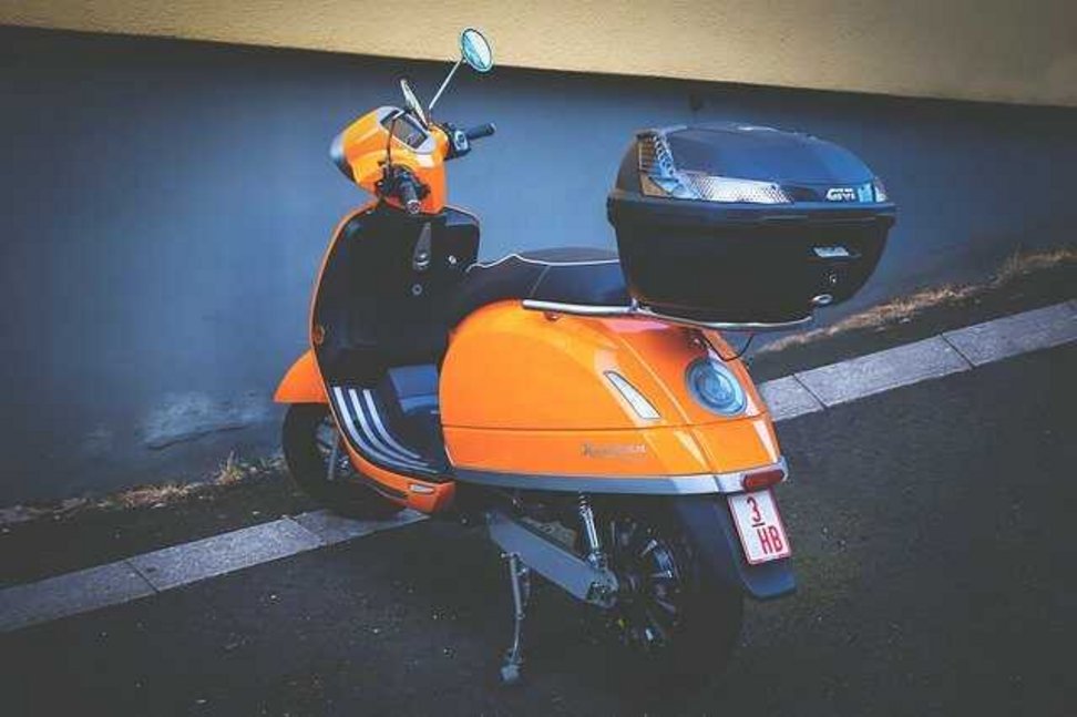 zaparkowany pomarańczowy skuter z bagażnikiem