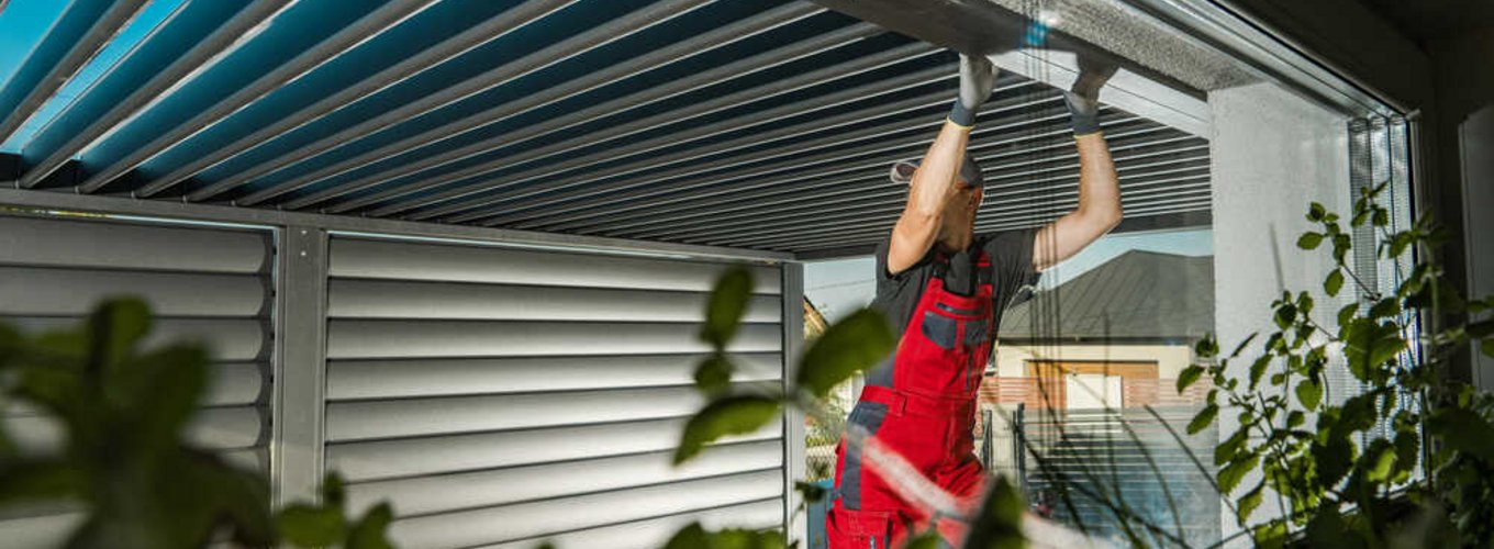 Mężczyzna buduje wiatę garażową. Spogląda na to, czy dobrze wykonał pracę.