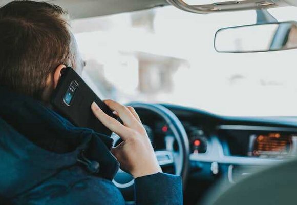 widok z tylnego siedzenia pasażera na kierowcę rozmawiającego przez telefon w zaparkowanym samochodzie