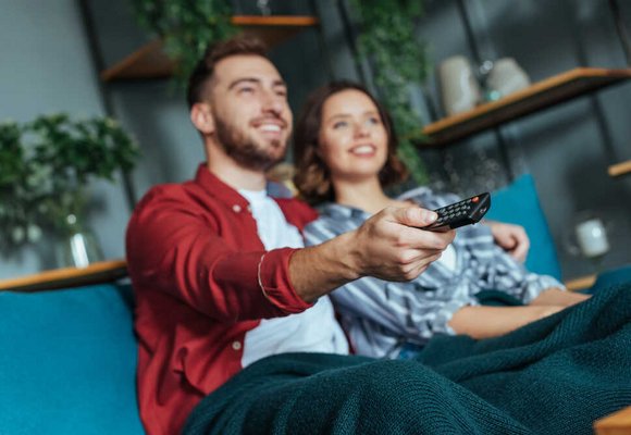 Para ogląda filmy o finansach na tablecie w domowym zaciszu, mężczyzna trzyma pilota do telewizora, edukacja finansowa w wygodnej atmosferze. Para ogląda filmy o finansach na tablecie w domowym zaciszu, mężczyzna trzyma pilota do telewizora, edukacja finansowa w wygodnej atmosferze.