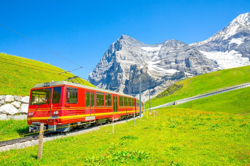 Czerwony pociąg jadący przez alpejski krajobraz w Szwajcarii – malownicze widoki i podróż Glacier Express