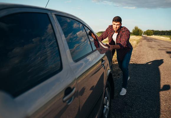 mężczyzna pcha zepsute auto