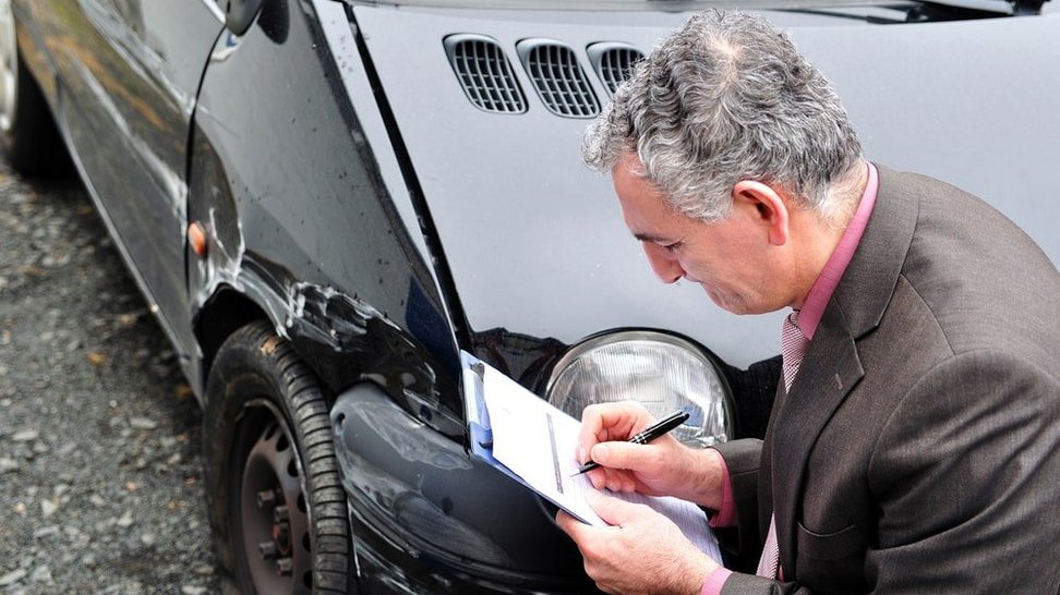 Mężczyzna spisujący dokument zdarzenia drogowego