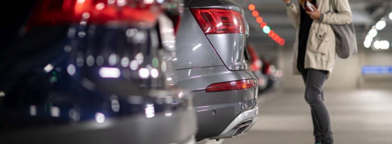 Kobieta stoi przy samochodzie i sprawdza, gdzie znajdzie tabliczkę znamionową