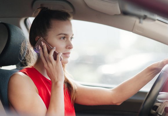 kobieta za kierownicą rozmawia przez telefon