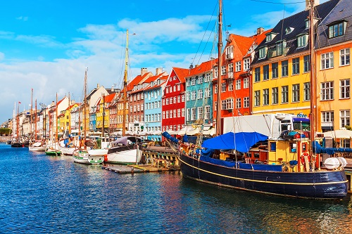 Kolorowe budynki i łodzie wzdłuż nabrzeża w Nyhavn, Kopenhaga, pod jasnym, błękitnym niebem.