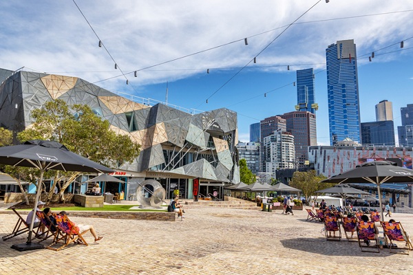 People enjoy the summer weather in Federation Square, Melbourne, Australia.