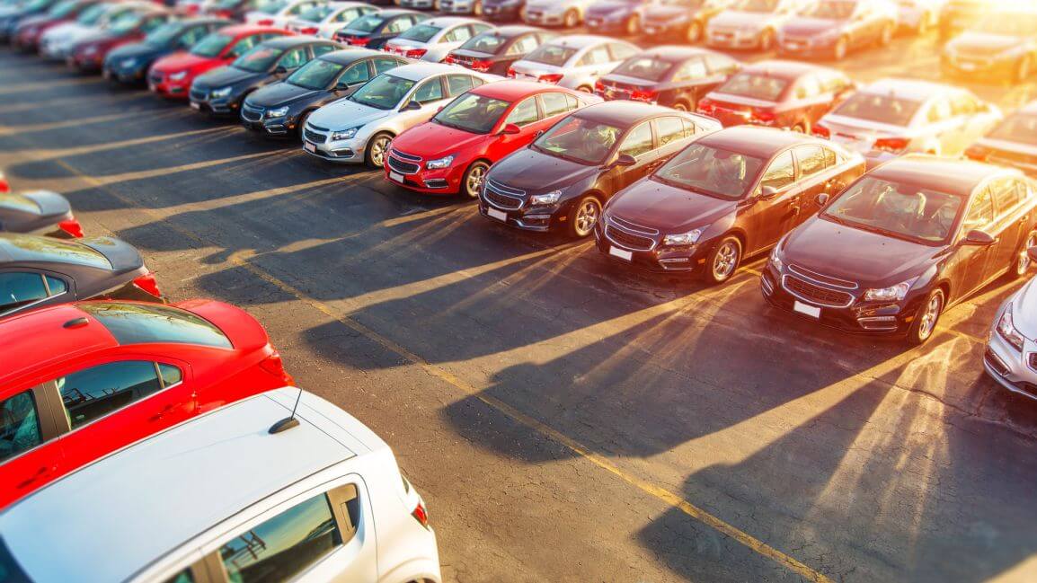 Na parkingu stoją różne modele aut i wszystkie wymagają opłacenia podatku od zakupu samochodu