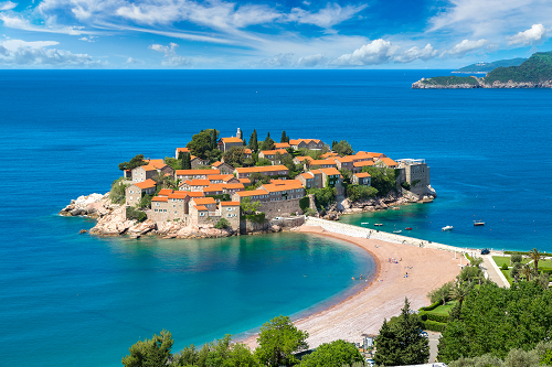 Wyspa Sventi Stefan w Czarnogórze, otoczona turkusowym morzem i piaszczystą plażą.