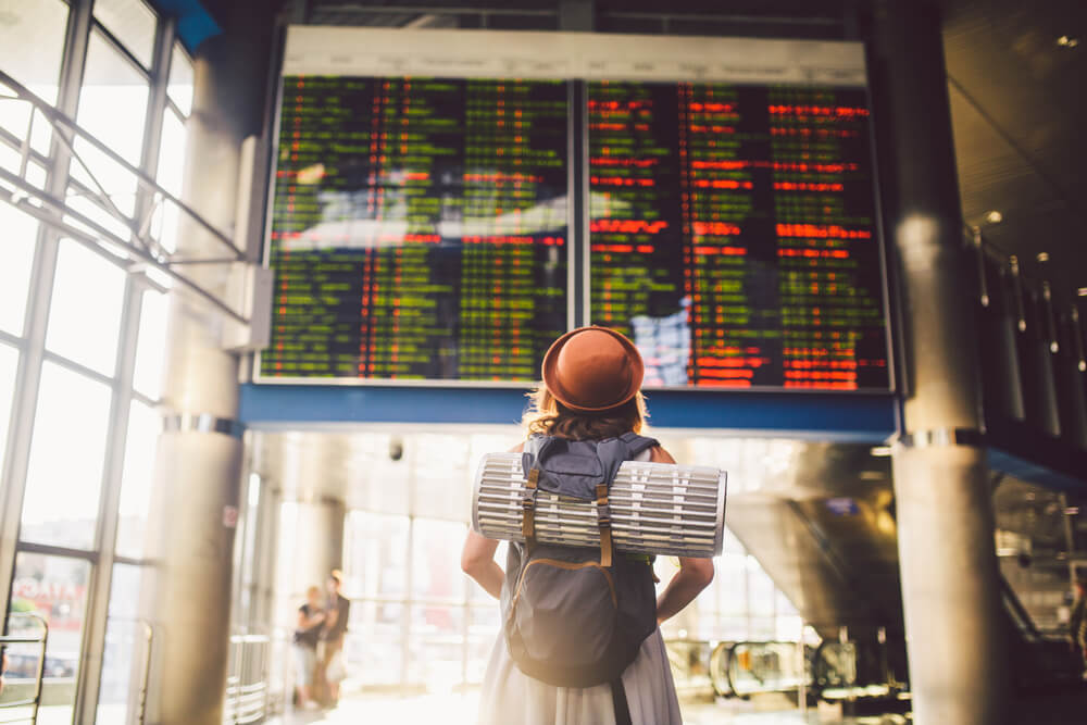 młoda dziewczyna sprawdza swój lot na tablicy odlotów